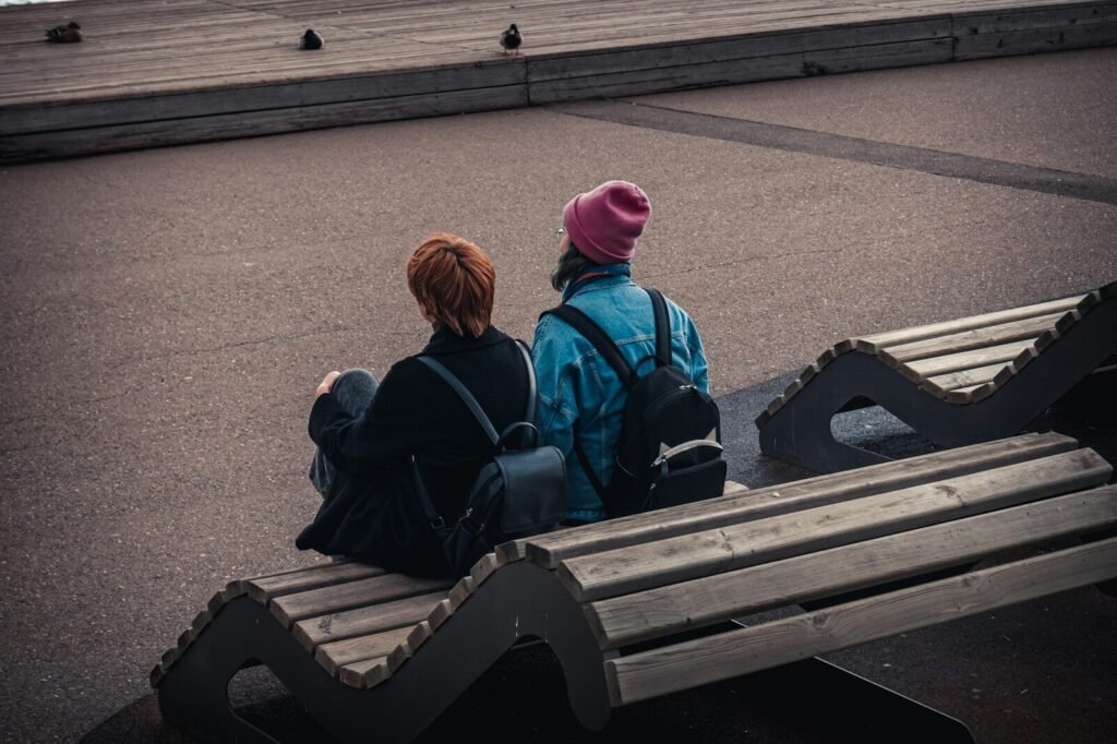 Two people sit on a bench together.