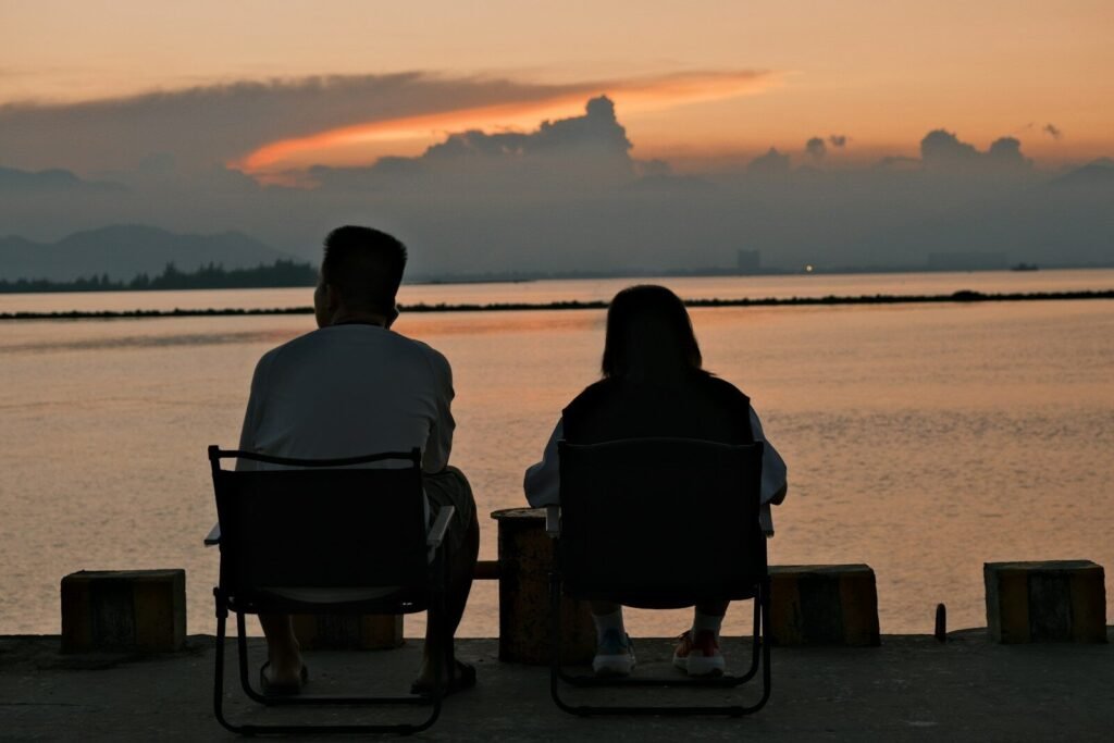 Two people sitting on a bench watching the sunset