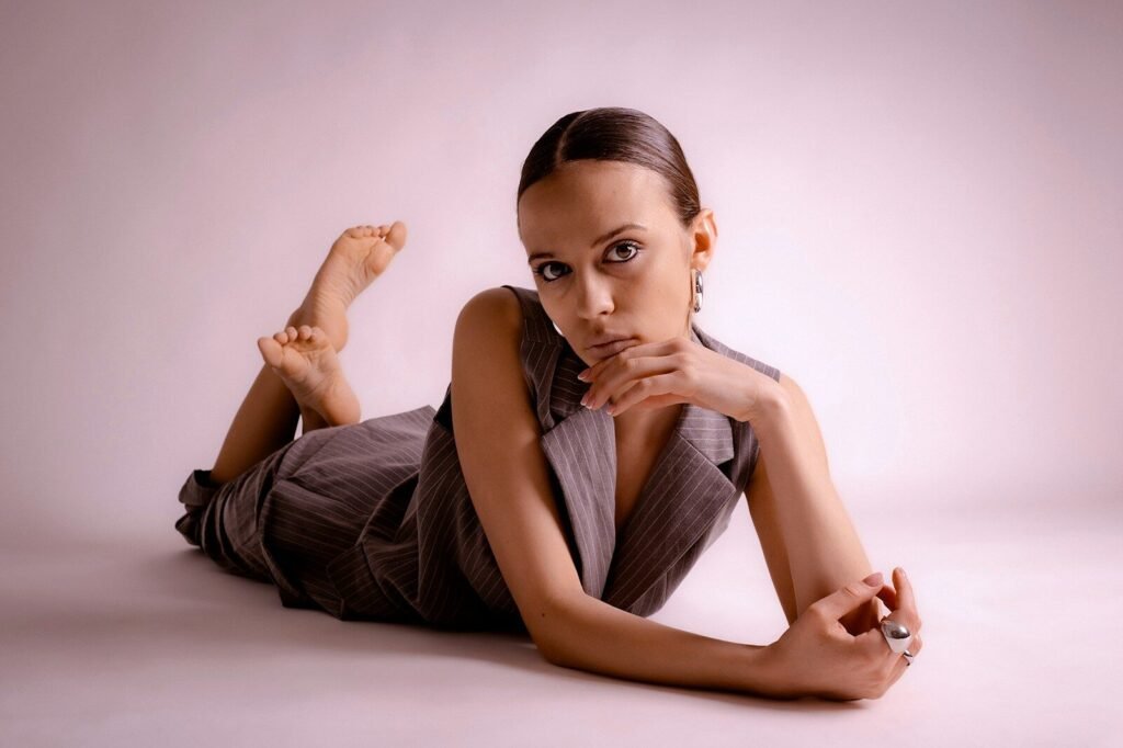 A woman in a grey vest lies on the floor.