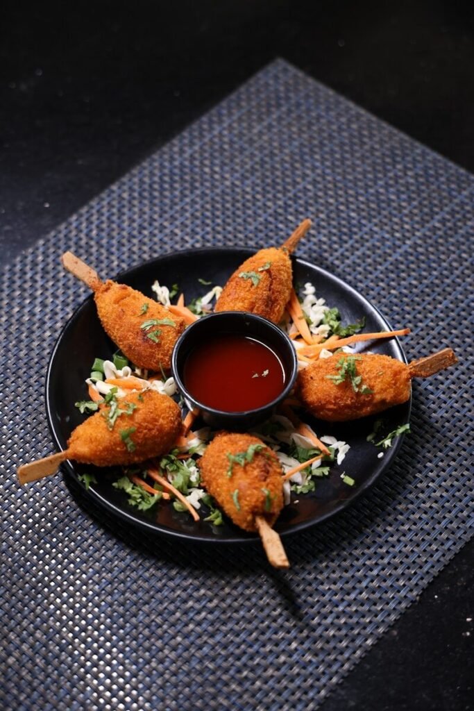 A black plate topped with fried food and dipping sauce