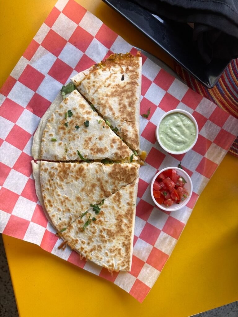 A quesadilla cut in half on a red and white checkered paper