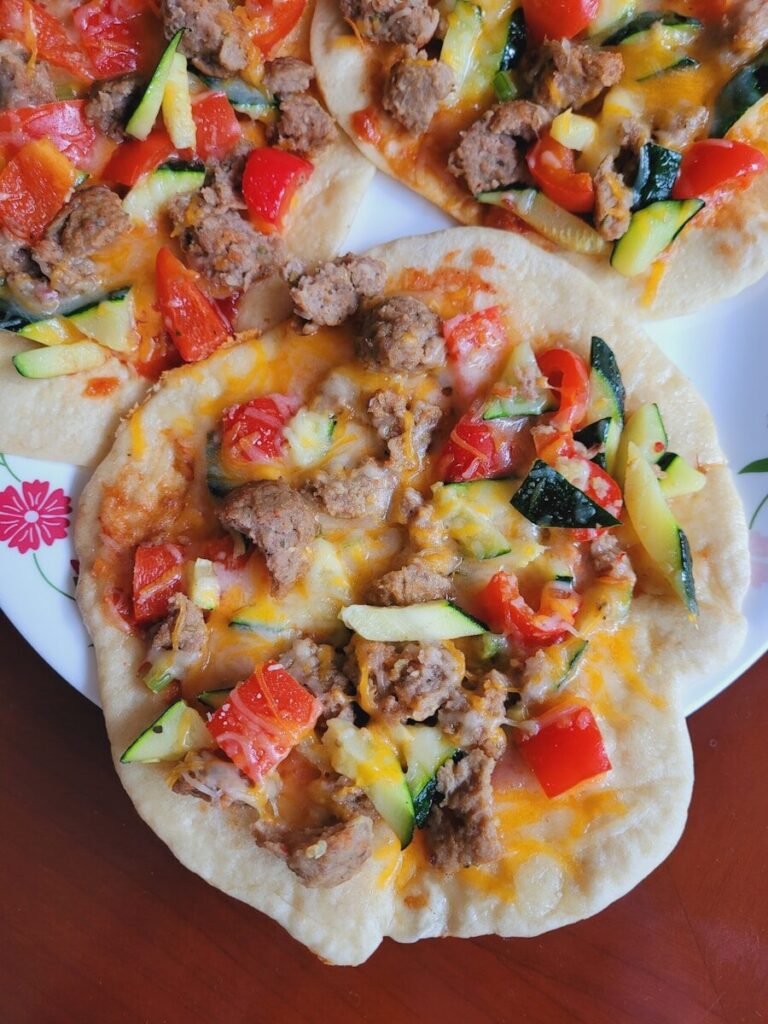 a white plate topped with three tortillas covered in meat and veggies